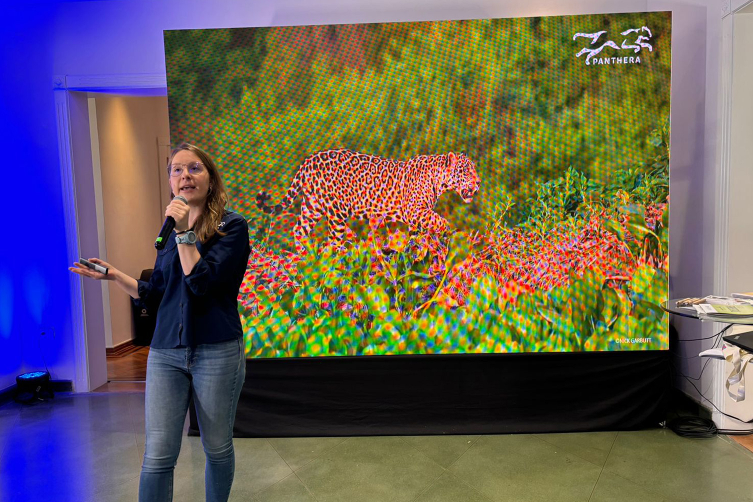 Woman speaking in front of screen of a jaguar photo