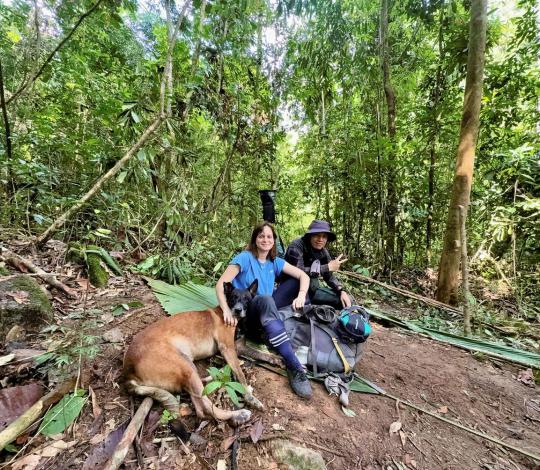 Dog and two people sit on the ground