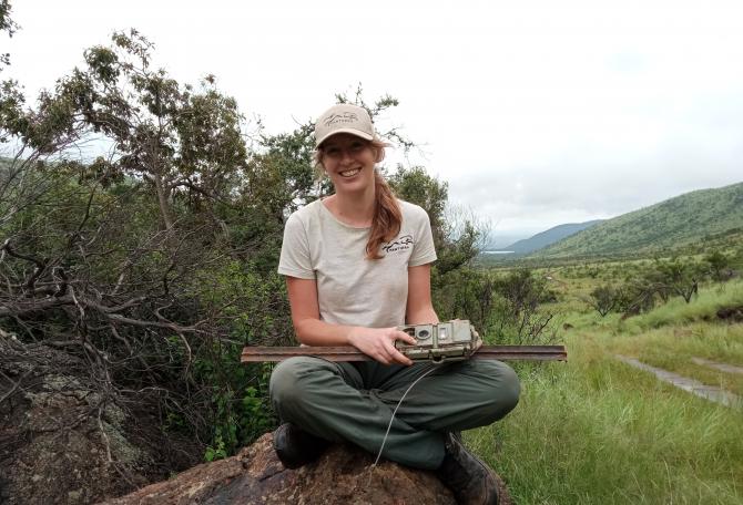 Woman sitting down with poacher cam and smiling at camera