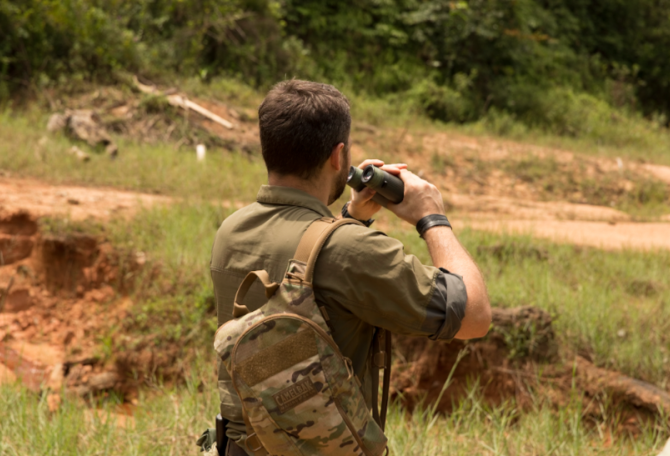 Man looking at a distance holding binoculars.